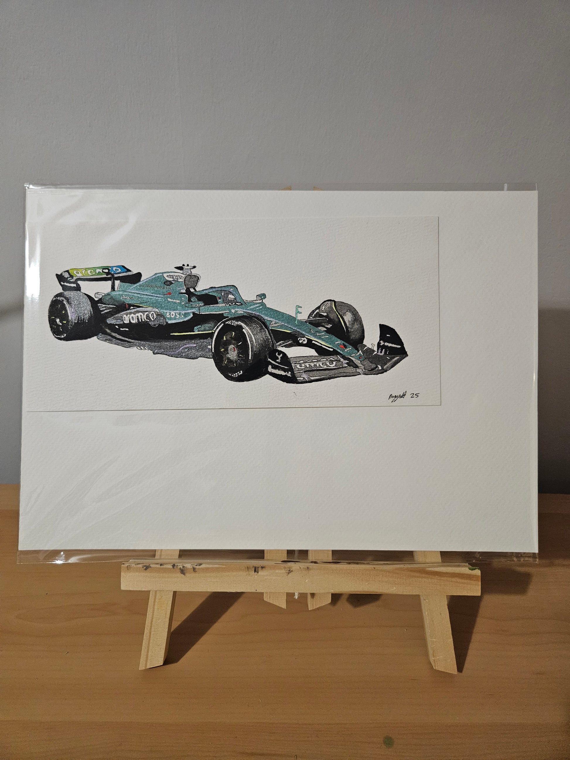 Artistic depiction of a F1 Aston Martin 2025 car on a white sheet of paper with a wooden easel.